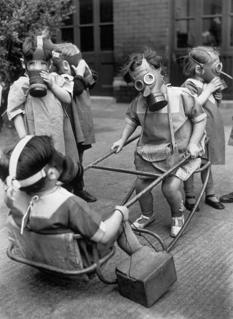 Niños y niñas jugando en la calle con máscaras de gas (1940)